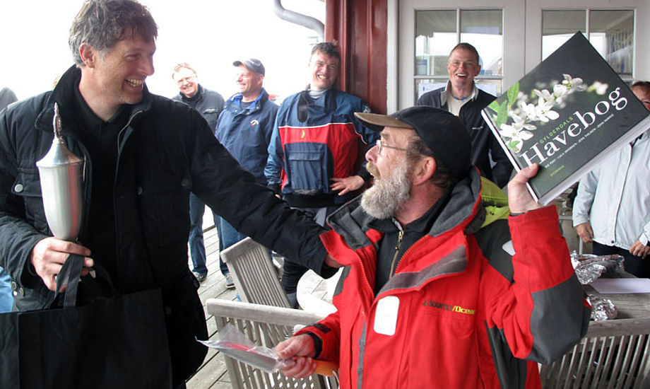 Jørgen Svendsen får havebog i præme af Lundeborg Sejlklubs stævneleder, der gav kommunesammenlægningen skylden for det regnfulde vejr. Foto: Troels Lykke