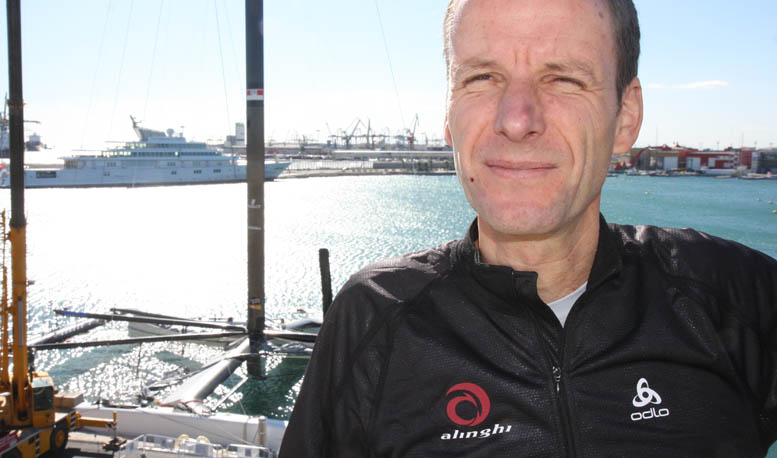 Michael Richelsen med ´Alinghi 5' i baggrunden i Valencia. Katamaranens buede sværd hjælper i øvrigt båden op af vandet. Foto: Troels Lykke