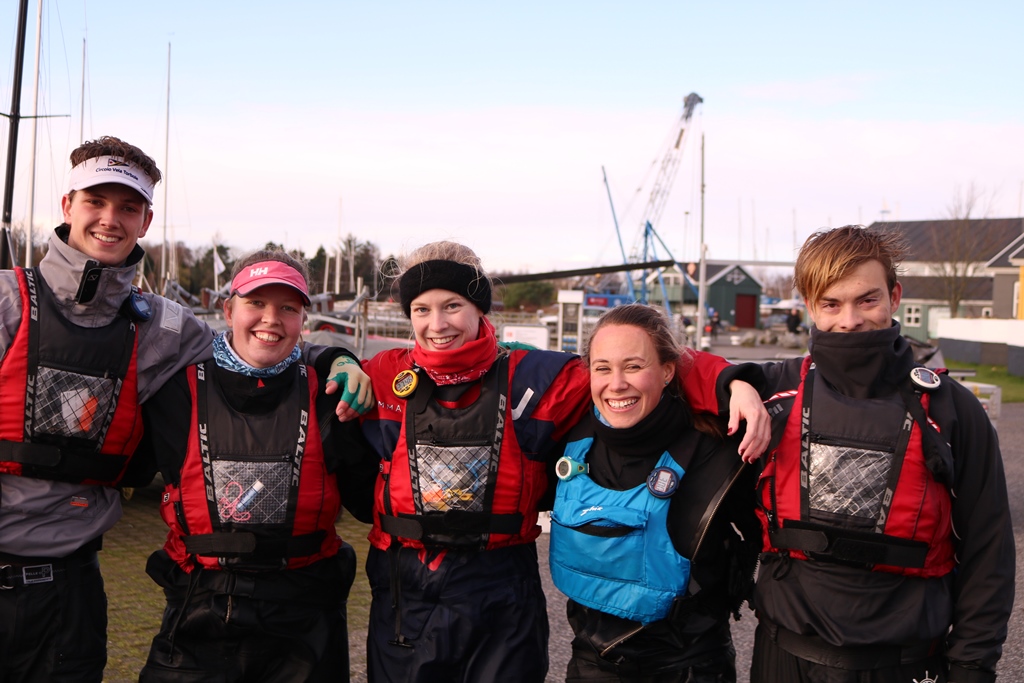 Der var stadig smil på læberne hos sejlerne efter en lang og kold dag på vandet. Fra Venstre: Nikolai Tiedemann, Maria Ravn, Julie Skovbo, Marisa Roch og Sophus Jarvig.  Foto: Rune Cramer.