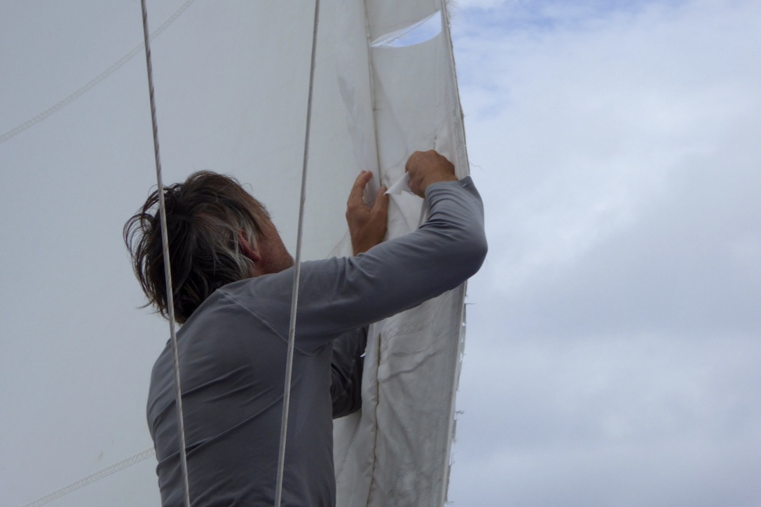 Henrik reparerer genuaen med sejltape. Foto: Signe Storr